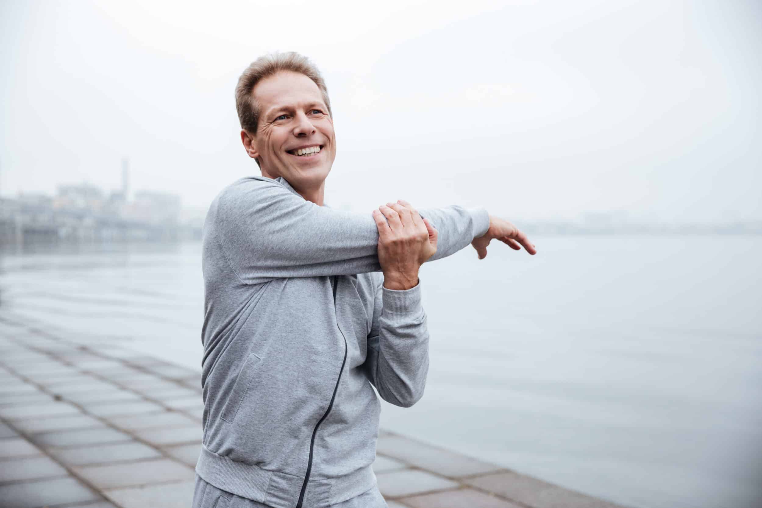 A man in a gray jacket stretching his shoulder