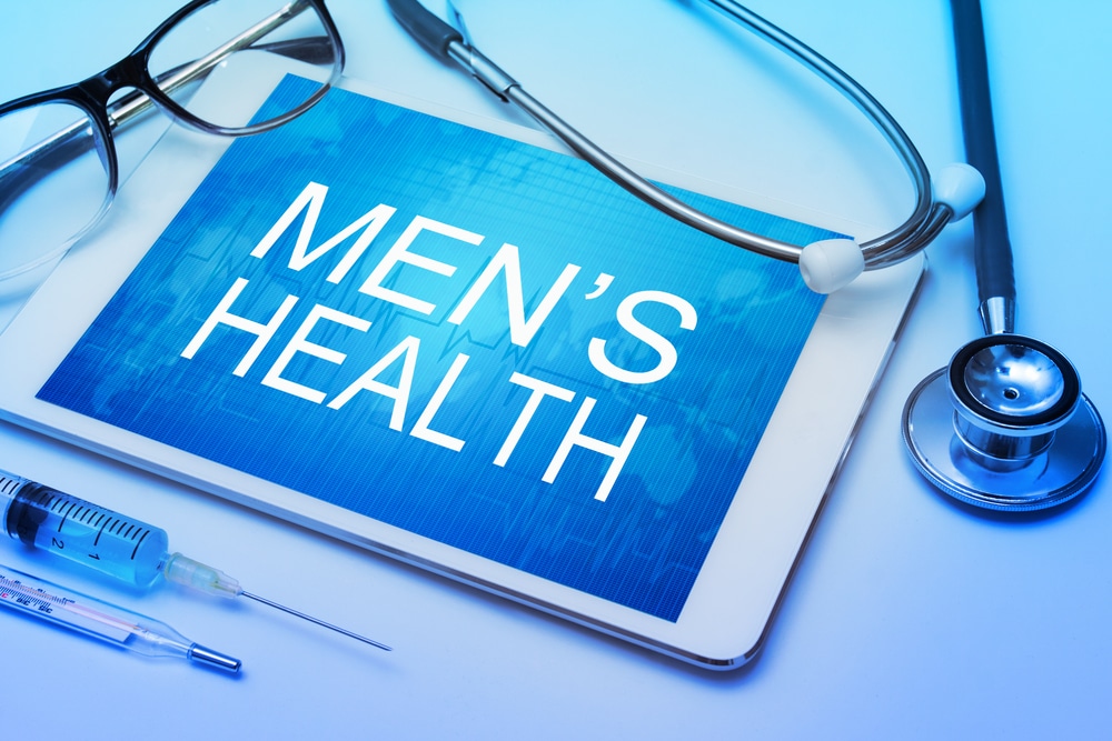 A stethoscope on a table with a tablet that says “Men’s Health”
